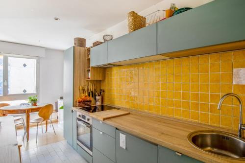 - une cuisine avec du carrelage jaune sur le mur dans l'établissement Appartement Molière - Welkeys, à Avignon