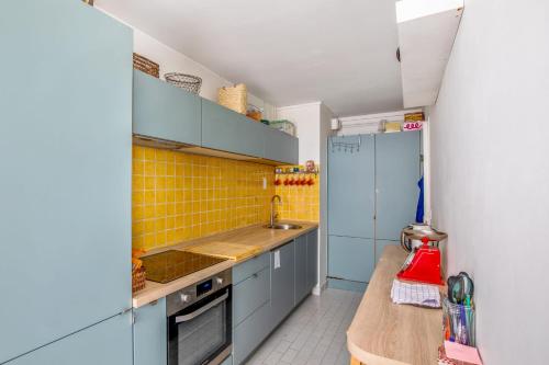 une petite cuisine avec des armoires bleues et du carrelage jaune dans l'établissement Appartement Molière - Welkeys, à Avignon