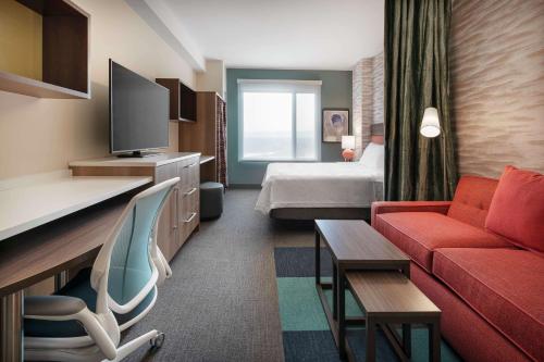 una camera d'albergo con un divano rosso e un letto di Home2 Suites By Hilton Denver Downtown Convention Center a Denver