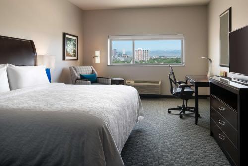 a hotel room with a bed and a desk and a window at Hilton Garden Inn Denver/Cherry Creek in Denver