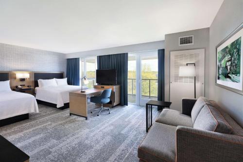 a hotel room with a bed and a desk and a couch at Hampton Inn & Suites Watertown Boston, Ma in Watertown