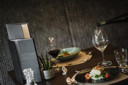 a table with a plate of food and wine glasses at Klein Fein Hotel Anderlahn in Parcines