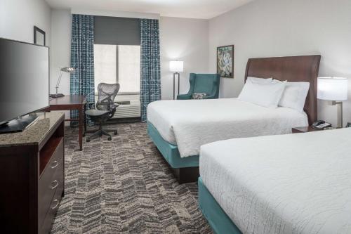 a hotel room with two beds and a flat screen tv at Hilton Garden Inn DFW North Grapevine in Grapevine