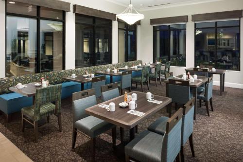 a restaurant with wooden tables and chairs and windows at Hilton Garden Inn Tucson Airport in Tucson