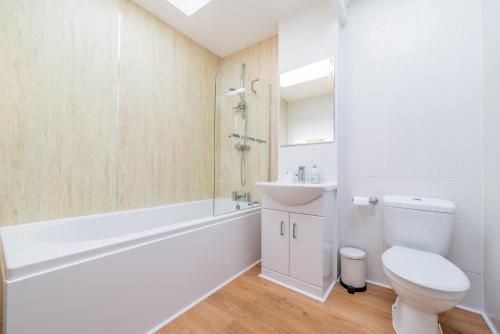 a white bathroom with a toilet and a sink at The Decker Apartment in Looe