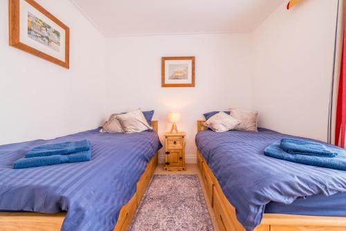 two twin beds in a room with a night stand at The Decker Apartment in Looe