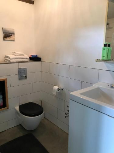 a bathroom with a toilet with a black seat and a sink at Mamas Cabin in Laag-Soeren
