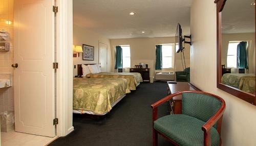 a hotel room with two beds and a chair at Country Squire inn and suites in Coshocton