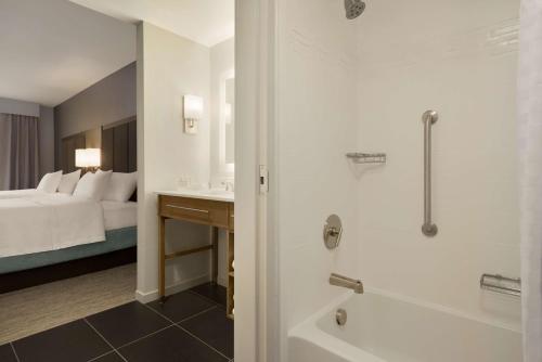 uma casa de banho com uma cama, um chuveiro e um lavatório. em Homewood Suites By Hilton Southaven em Southaven