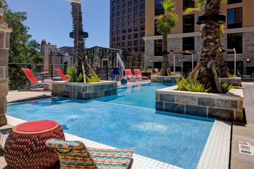 una piscina con sillas y palmeras en una ciudad en Home2 Suites By Hilton San Antonio Riverwalk, en San Antonio
