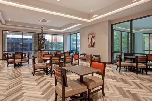 un comedor con mesas, sillas y ventanas en Home2 Suites By Hilton San Antonio Riverwalk, en San Antonio