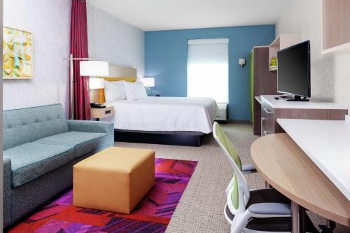 a hotel room with a bed and a couch at Home2 Suites By Hilton Orlando South Park in Orlando
