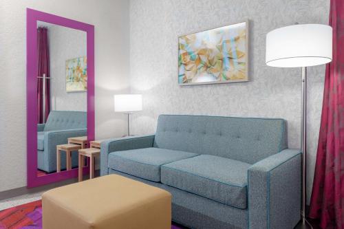 a living room with a blue couch and a mirror at Home2 Suites By Hilton Orlando South Park - Near Epic Universe in Orlando