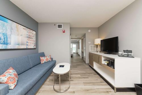 a living room with a blue couch and a tv at DoubleTree Suites by Hilton Melbourne Beach Oceanfront in Melbourne