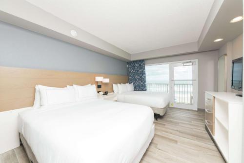 a hotel room with two beds and a window at DoubleTree Suites by Hilton Melbourne Beach Oceanfront in Melbourne