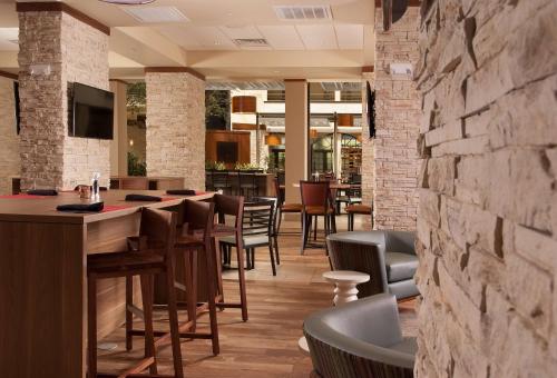 a restaurant with a stone wall and tables and chairs at Embassy Suites by Hilton Nashville Airport in Nashville