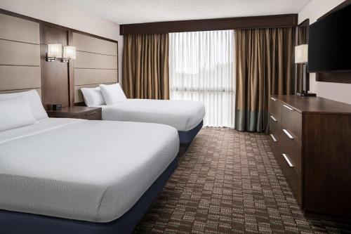 a hotel room with two beds and a television at Embassy Suites by Hilton Nashville Airport in Nashville