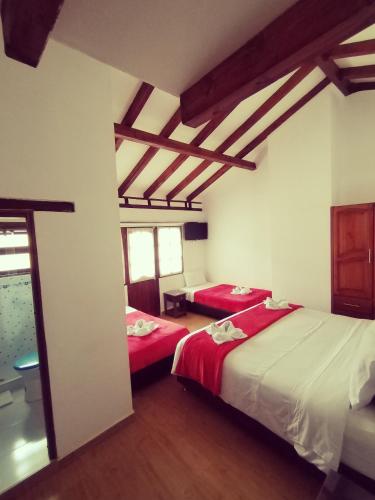 two beds in a room with wooden ceilings at Hospederia Sandaned in Villa de Leyva