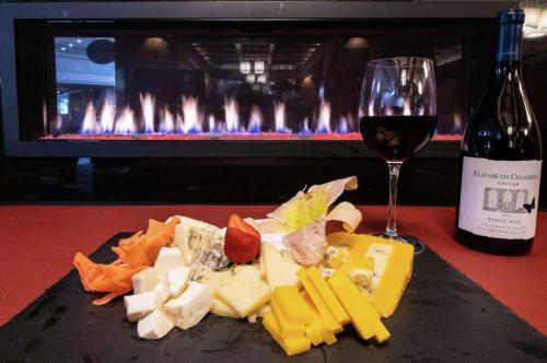 a plate of cheese and a glass of wine and a fireplace at DoubleTree by Hilton Portland in Portland