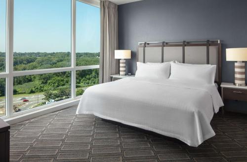 a bedroom with a large white bed and large windows at Homewood Suites By Hilton Teaneck Glenpointe in Teaneck