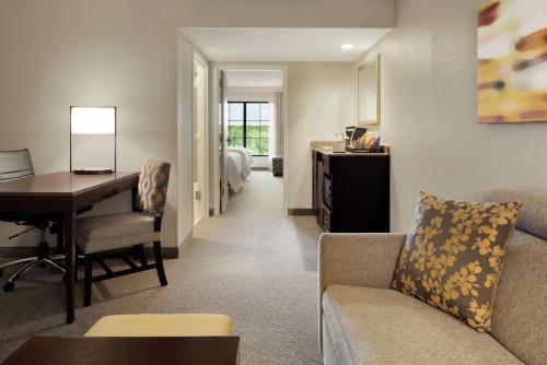 a living room with a couch and a desk in a room at Embassy Suites by Hilton Atlanta Alpharetta in Alpharetta