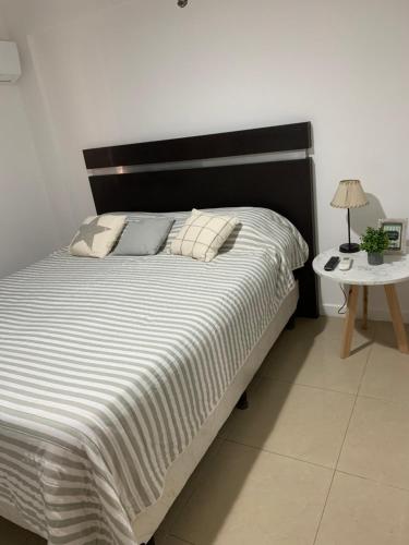 a bed with a black and white comforter and a table at Departamento Centro in Santiago del Estero