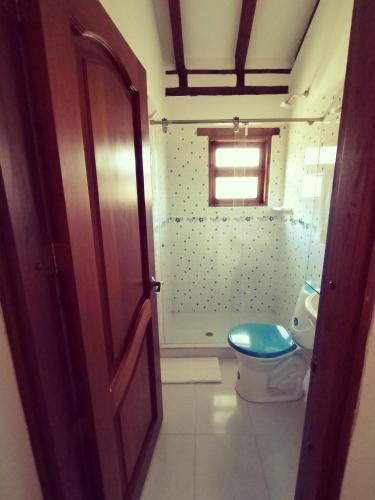 a bathroom with a blue toilet and a window at Hospederia Sandaned in Villa de Leyva