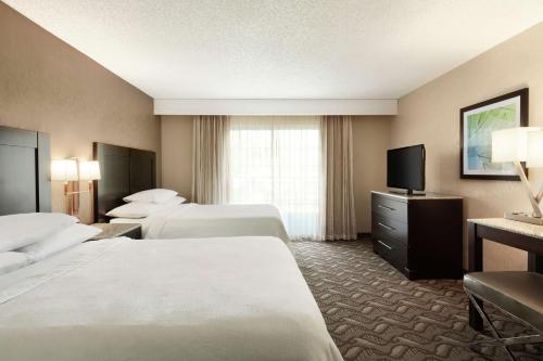a hotel room with three beds and a flat screen tv at Embassy Suites by Hilton Arcadia-Pasadena Area in Arcadia