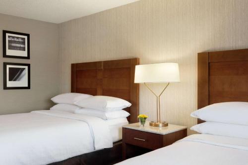 a hotel room with two beds and a lamp at Embassy Suites by Hilton Santa Ana Orange County Airport in Santa Ana