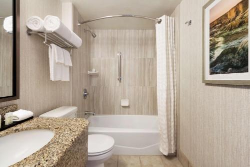 a bathroom with a tub and a toilet and a sink at Embassy Suites San Luis Obispo in San Luis Obispo
