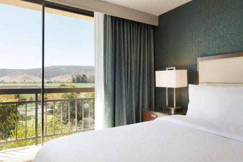 サンルイス・オビスポにあるエンバシー スイーツ サン ルイス オビスポのベッドと大きな窓が備わるホテルルームです。