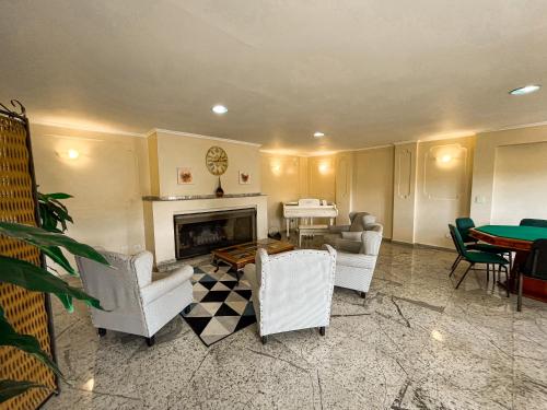a living room with white chairs and a fireplace at Hotel Nacional Inn Campos do Jordão in Campos do Jordão