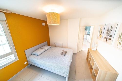 a bedroom with a bed and a yellow wall at Le Vénissieux-spacieux 4 pers avec balcon parking in Vénissieux