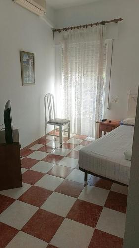 um quarto com uma cama e uma cadeira ao lado de uma janela em Hostal Alboran em Motril