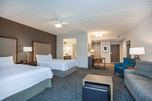 a hotel room with two beds and a couch at Homewood Suites By Hilton Saratoga Springs in Saratoga Springs