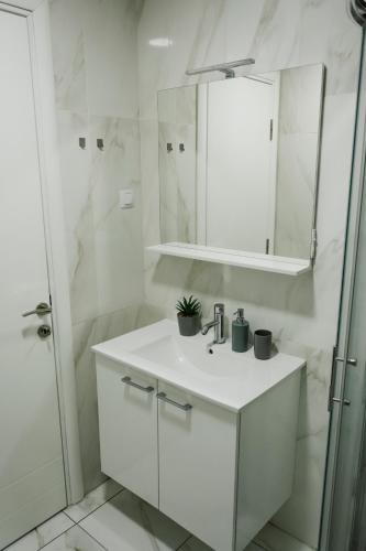 a white bathroom with a sink and a shower at Luka Apartments Flatiron in Skopje