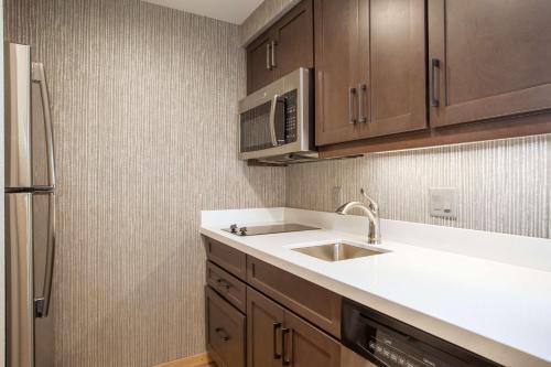 a kitchen with a sink and a refrigerator at Homewood Suites By Hilton Saratoga Springs in Saratoga Springs