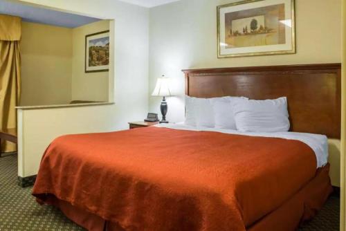 a hotel room with a large bed with a red blanket at Quality Inn & Suites Sioux City Southeast in Sioux City