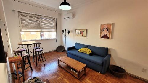 uma sala de estar com um sofá azul e uma mesa em Apartamento 1 quadra da praia no Rio de Janeiro