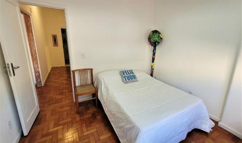 um pequeno quarto com uma cama e uma cadeira em Apartamento 1 quadra da praia no Rio de Janeiro