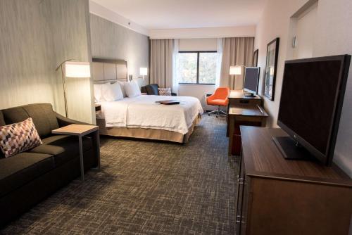 a hotel room with a bed and a flat screen tv at Hampton Inn Albany-Western Ave/University Area, NY in Albany