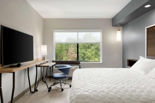 a bedroom with a bed and a desk and a television at Tru by Hilton Albany Crossgates Mall in Albany