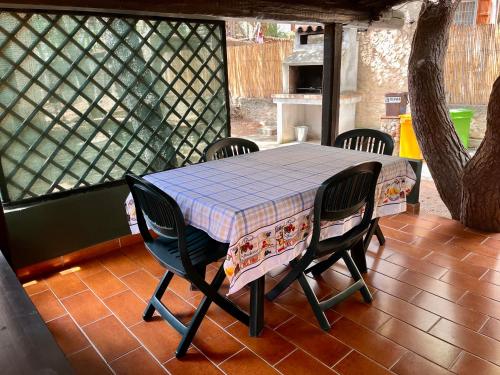 Una mesa y sillas en un porche cubierto con una mesa y una mesa y sillas. en Rustico Porto Pino 30 mt dalla spiaggia, en Porto Pino