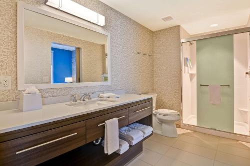 a bathroom with a sink and a toilet and a mirror at Home2 Suites By Hilton Naples I-75 Pine Ridge Road in Naples