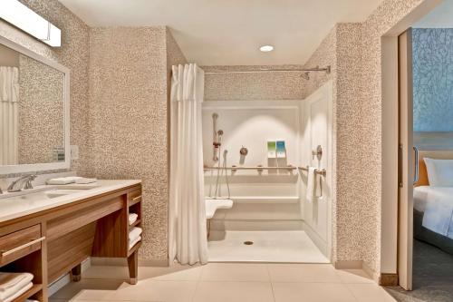 a bathroom with a tub and a sink and a shower at Home2 Suites By Hilton Naples I-75 Pine Ridge Road in Naples