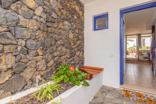 una pared de piedra en una casa con un banco en Adosado Maday Azul, Los Cancajos en Breña Baja
