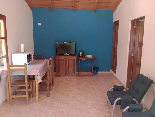 uma sala de estar com uma parede azul e uma mesa e uma televisão em El oso viejo em Puerto Iguazú