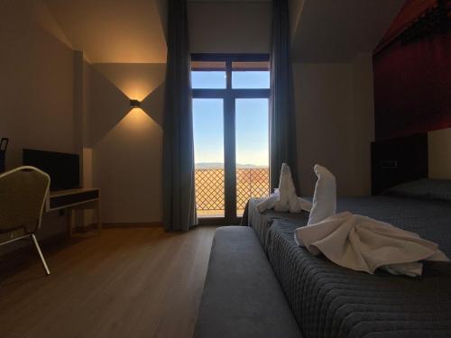 a bedroom with a bed with a large window at Hotel-Asador Montes Oretanos in Pulgar
