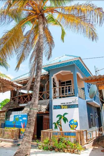 a palm tree in front of a building at PALM - 2minutes walk to the beach in Nungwi