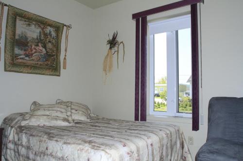 1 dormitorio con cama y ventana en Gite La Ptite Falaise hébergement touristique en Sainte-Anne-des-Monts